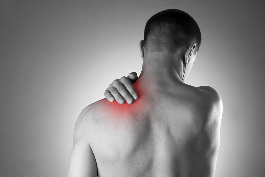 Man with pain in shoulder. Pain in the human body. Black and white photo with red dot